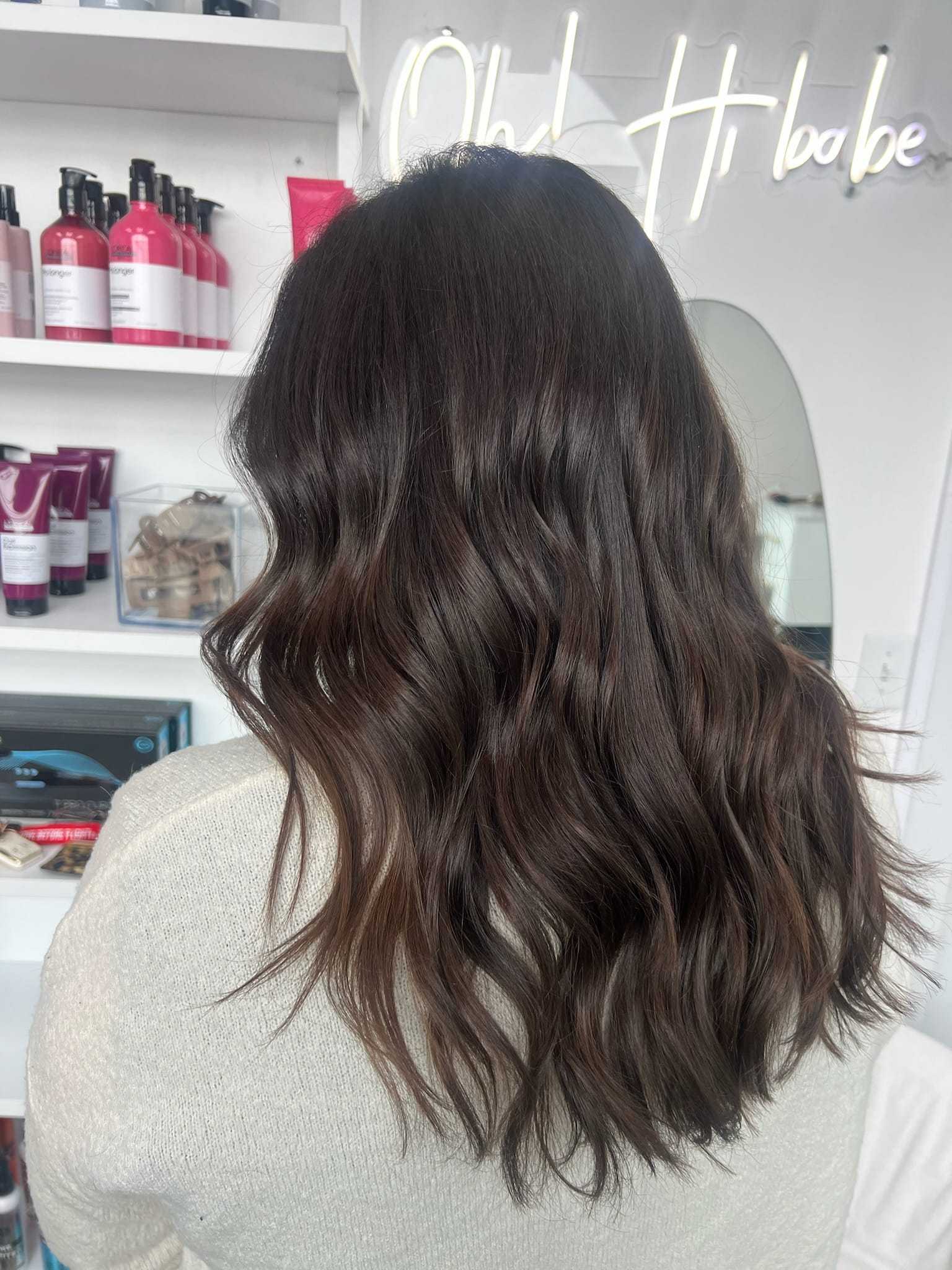 Person with wavy brunette hair at a hair salon.